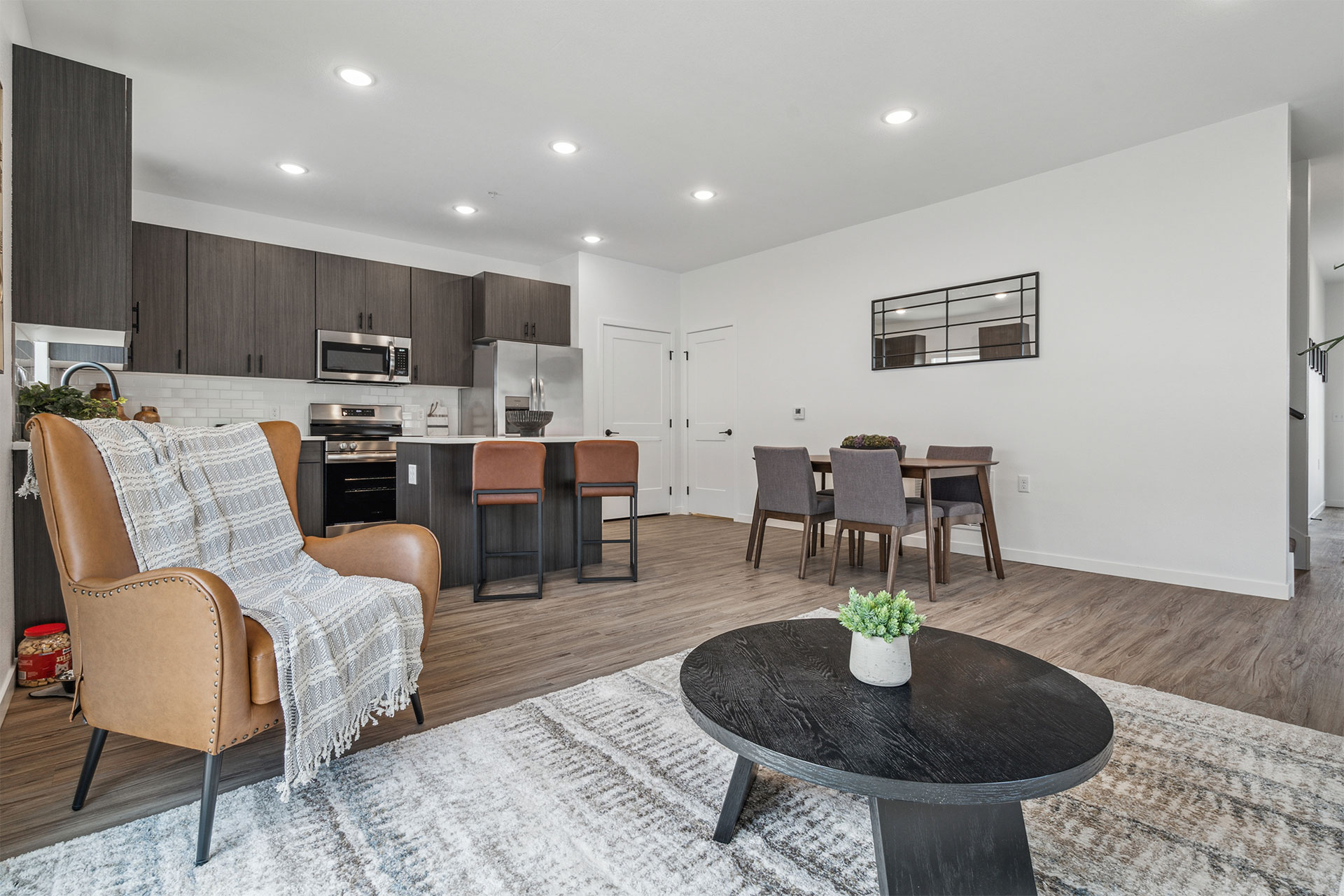 Open-plan living room and kitchen with dining area, leather chair, and coffee table