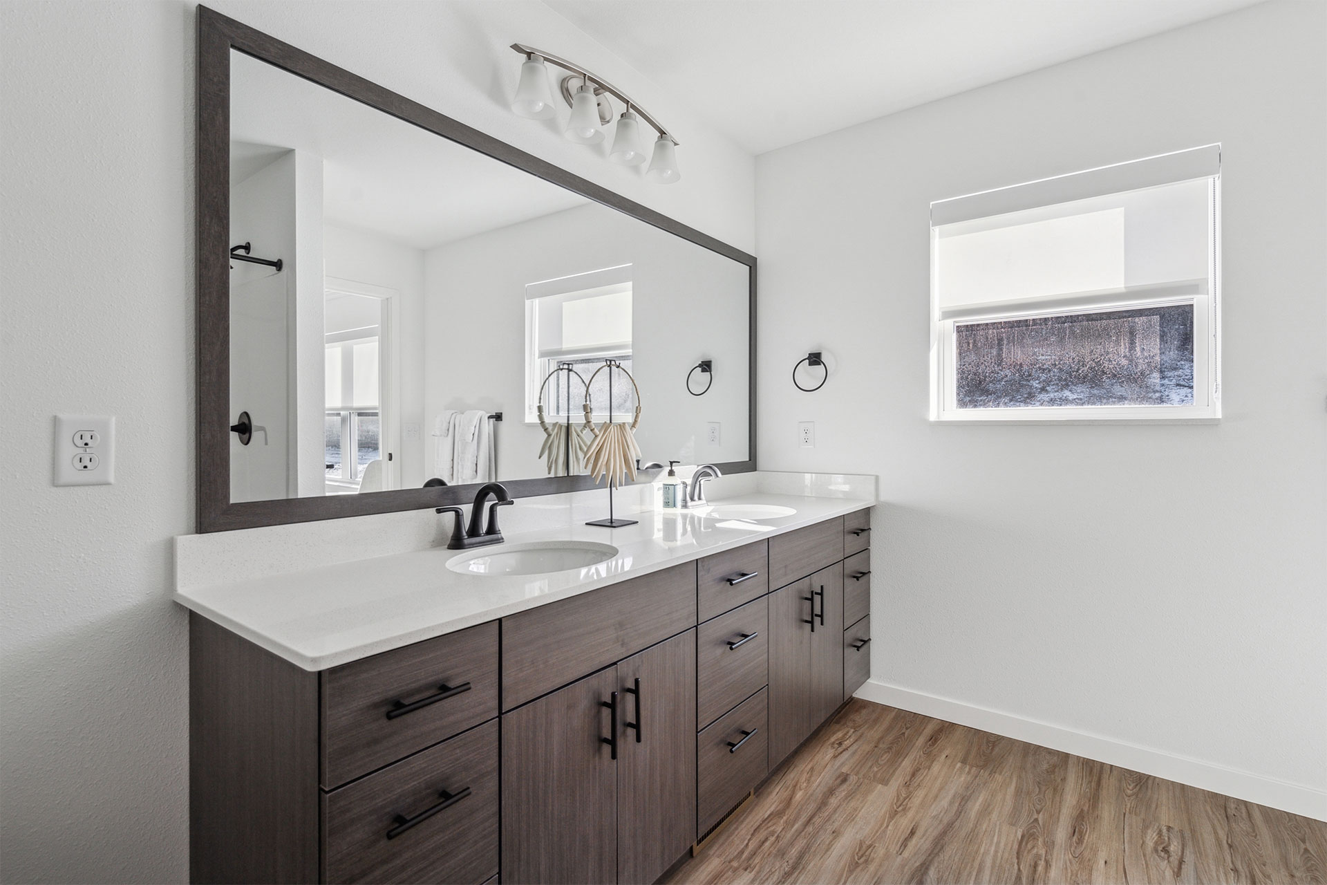 Modern bathroom vanity with double sinks, large mirror, and wood cabinetry