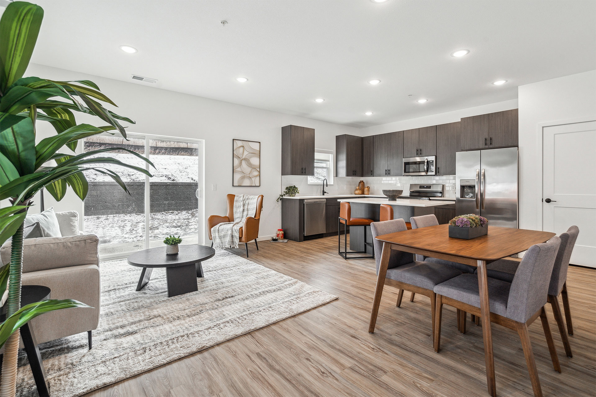 Open-concept living and dining area with kitchen, modern furniture, and large sliding glass doors